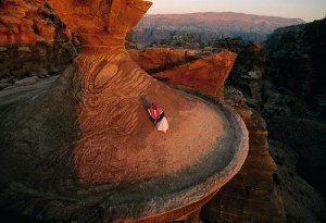 A Bedouin man sitting on top of one of the ancient buildings of Petra ( Jordan), photo by Annie Griffiths